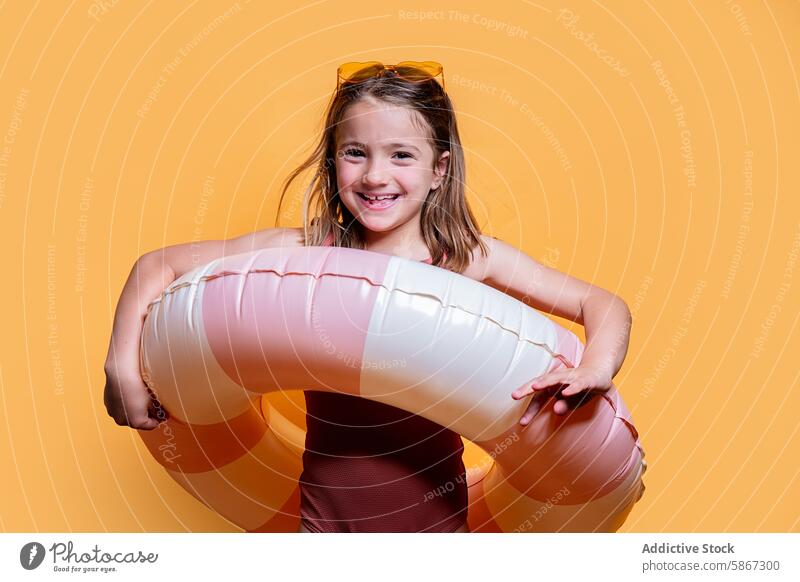 Junges Mädchen mit aufblasbarem Ring im Sommer Studio schießen Atelier gelb Hintergrund spielerisch heiter Lächeln Sonnenbrille Kind Pose strahlend sorgenfrei