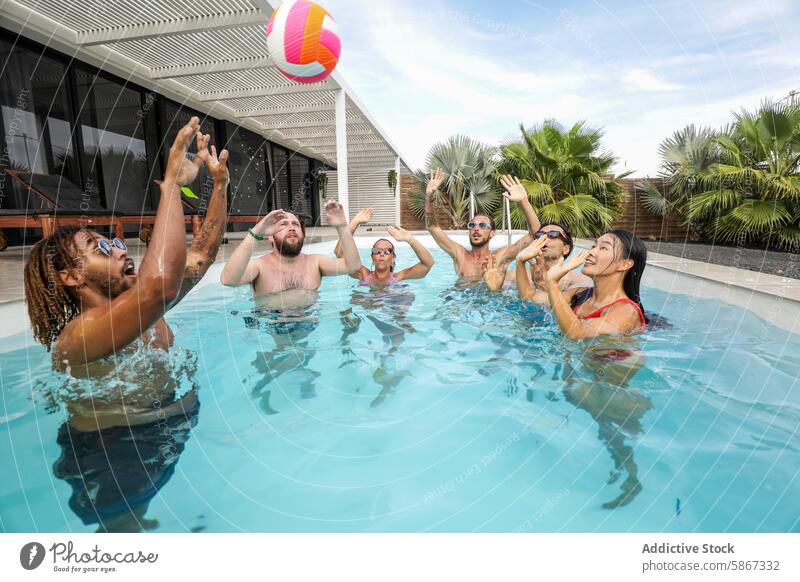 Freunde spielen während eines Sommertreffens Ball im Pool Spielen Spaß Wasser Geplätscher heiter Menschengruppe im Freien multiethnisch Party Vielfalt Sammeln