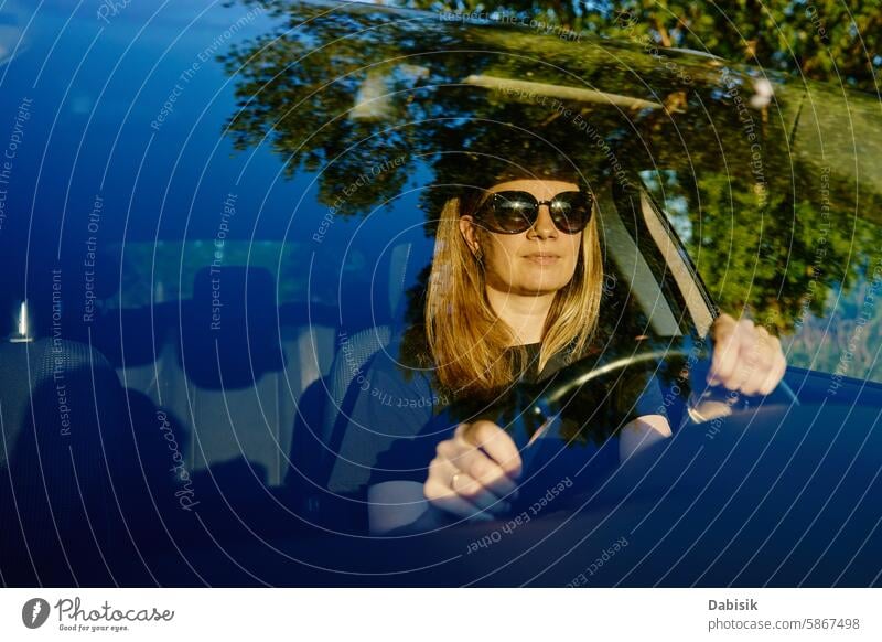 Eine glückliche Frau sitzt im Auto. Blick durch die Windschutzscheibe PKW Fahrer genießen Glück fahren Fahrzeug achtsam reisen Erwachsener attraktiv schön