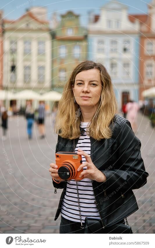 Weiblicher Reisender, der ein Bild mit einer alten Sofortbildkamera aufnimmt Tourist sofort Fotokamera reisen Frau Tourismus Fotografie altehrwürdig