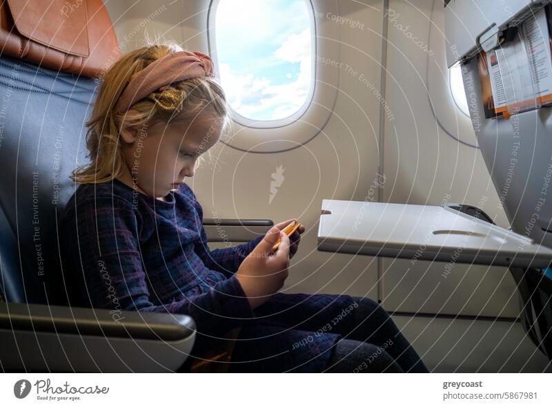 Kaukasisches Mädchen sitzt im Flugzeugsitz Sitz Fenster Spielzeug Kaukasier jung Kind Innenbereich Fluggerät reisen Passagier Sitzen Spielen Verkehrsflugzeug