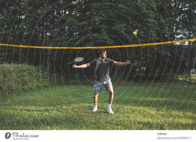 Ein schwarzhaariger Badmintonspieler übt seine Schläge auf dem Rasenplatz. Individuelles Techniktraining. Das Amateurkonzept des Sports. Die Freude am Spiel