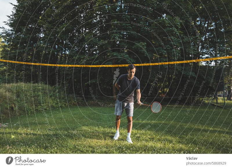 Ein schwarzhaariger Badmintonspieler übt seine Schläge auf dem Rasenplatz. Individuelles Techniktraining. Das Amateurkonzept des Sports. Die Freude am Spiel