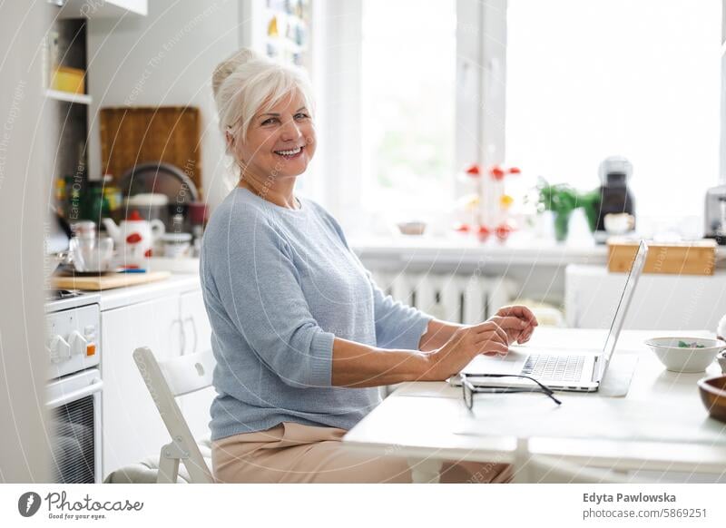 Ältere Frau mit Laptop sitzt am Tisch in der Küche Menschen Senior reif älter heimwärts Haus alt Alterung häusliches Leben Großmutter Rentnerin