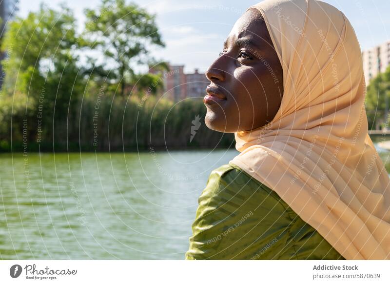 Frau im Hidschab genießt einen sonnigen Tag am See Park Familie Hijab im Freien ruhig Freude Moment Gelassenheit Wasser Bäume Erholung friedlich Bonden Freizeit