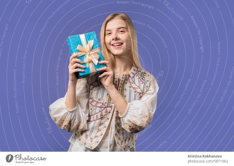 Glückliches Teenager-Mädchen mit Geschenkbox, violette Wand. Lächelnd, interessiert was drin ist Erwachsener attraktiv Hintergrund schön Schönheit Geburtstag