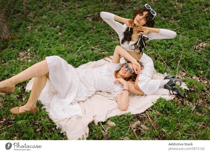 Entspannende Momente von zwei Freundinnen im Wald Erholung Natur im Freien Frau Decke Lügen Sonnenbrille Glück Stil weißes Kleid Freizeit friedlich Lächeln Gras