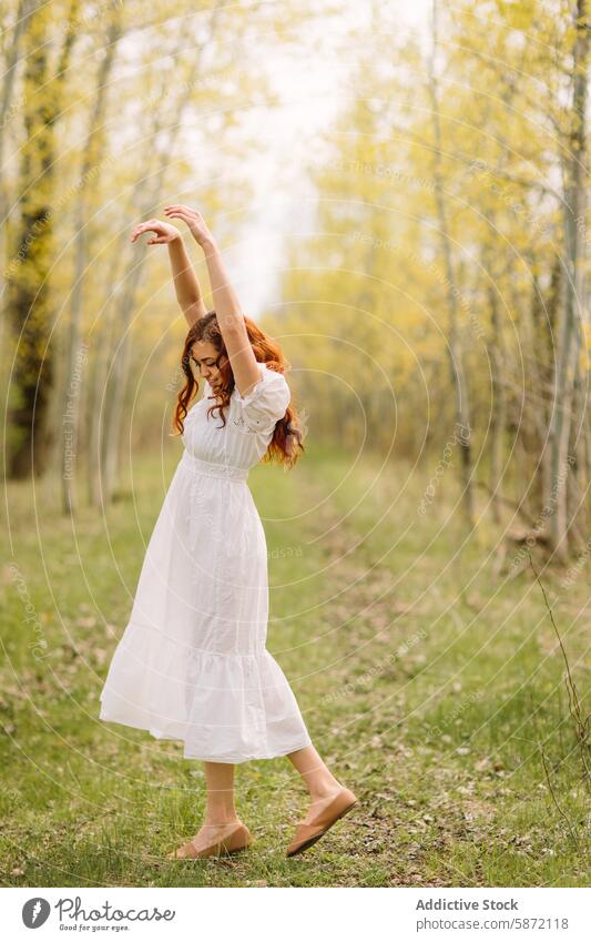 Junge Frau tanzt sorglos in einem Wald Tanzen Freiheit Freude Natur weißes Kleid krause Haare rote Haare Fröhlichkeit im Freien Frühling jugendlich sorgenfrei