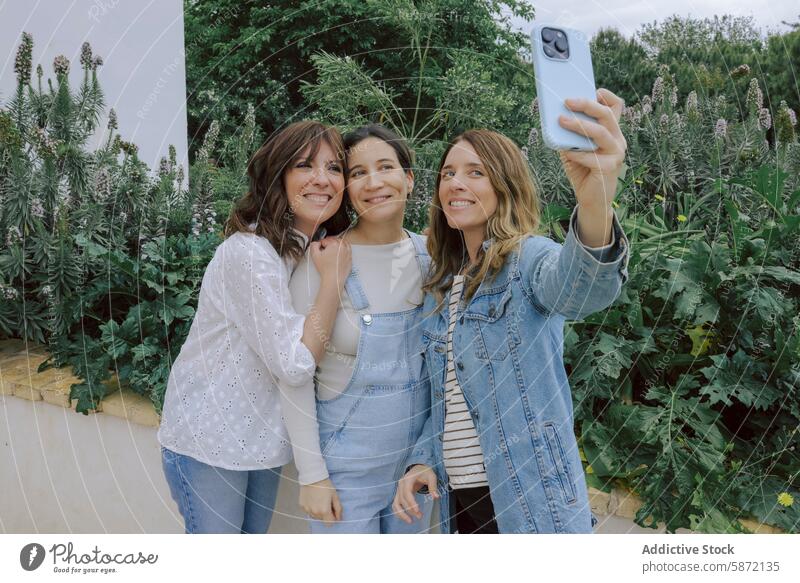 Drei Frauen machen zusammen ein Selfie in einem Garten Smartphone Fotokamera Lächeln Freundschaft Erwachsener Grün Freude heiter Technik & Technologie