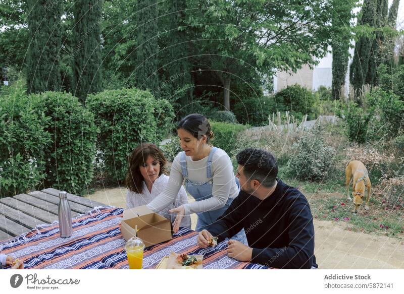 Freunde genießen ein Picknick mit Essen und Getränken im Freien Frauen Mann Hund Lebensmittel trinken Gespräch Grün Freizeit lässig Park Sommer Tag sozial