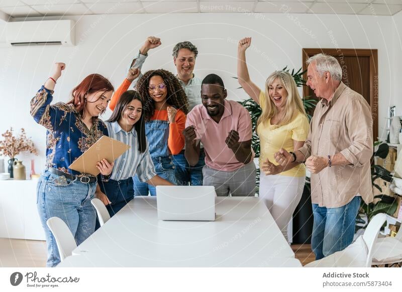 Vielfältiges Team feiert Erfolg im Coworking Space Feier Laptop Begeisterung Teamwork jubelnd multiethnisch vielfältig rassenübergreifend Männer Frauen Sitzung