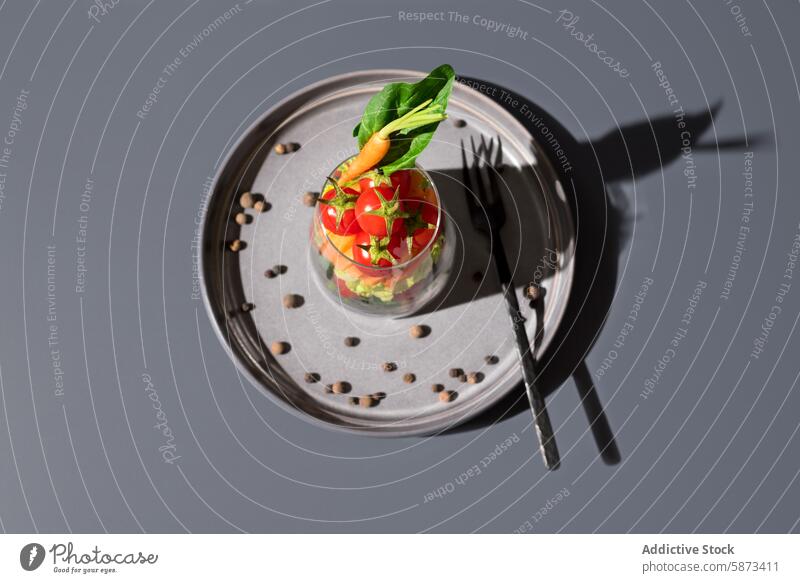 Draufsicht auf einen frischen Salat in einem Glas auf einem grauen Teller Salatbeilage Gemüse transparentes Glas grauer Hintergrund Gesundheit farbenfroh