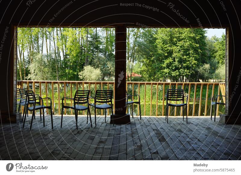 Stühle auf der Veranda eines Holzhaus in schöner Auenlandschaft mit Seerosen im Sommer bei Sonnenschein im Acarlar Auenwald bei Karasu in der Provinz Sakarya in der Türkei