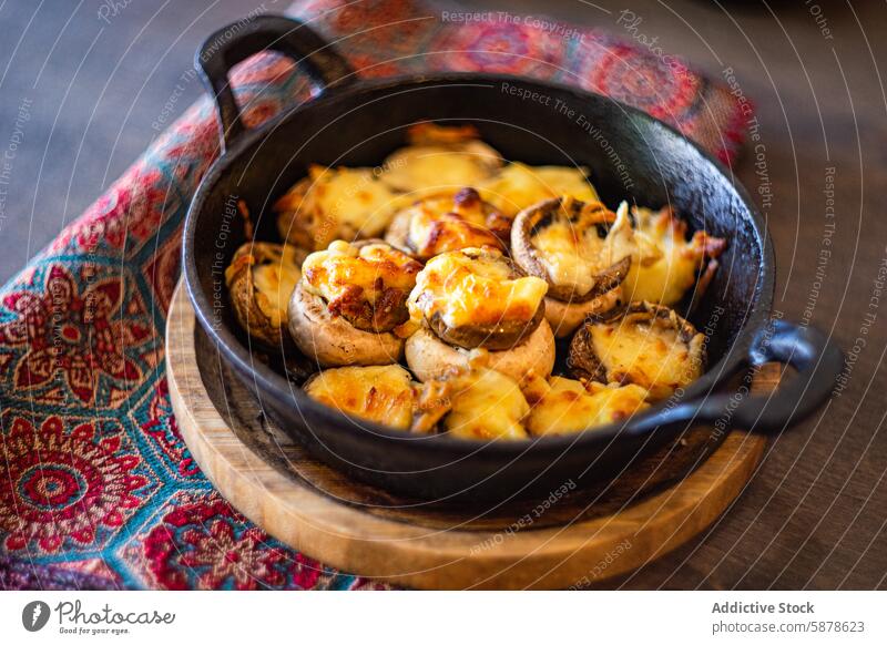 Gebackene Champignons gefüllt mit Sulguni-Käse in der Pfanne Pilz gebacken rustikal hölzern Tisch farbenfroh Gewebe Hintergrund Lebensmittel Speise Amuse-Gueule