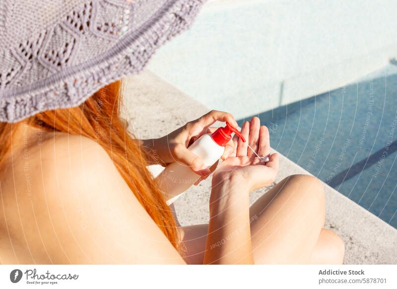 Frau, die sich im Sommer am Pool mit Sonnencreme eincremt Sonnenschutz Anwendung Schutz Hautpflege im Freien sonnig Tag Lifestyle Gesundheit sicher Wasser