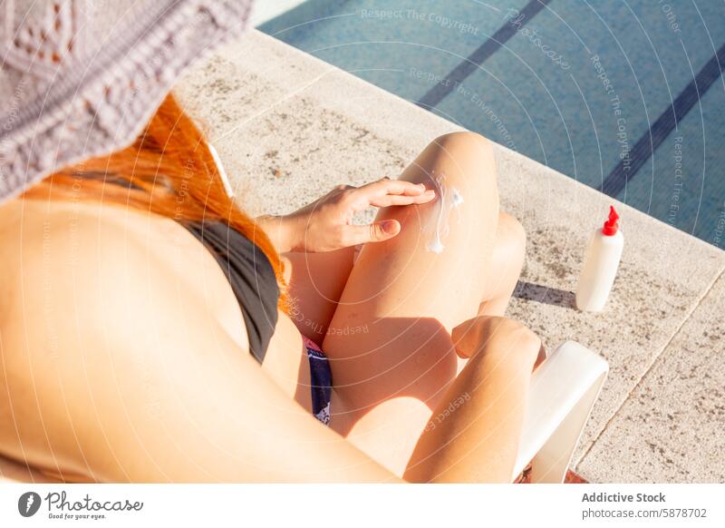 Unerkennbare Frau beim Auftragen von Sonnencreme am Pool im Sommer unkenntlich Sonnenschutz Lotion Haut Pflege Freizeit im Freien sonnig Tag Beckenrand Hut