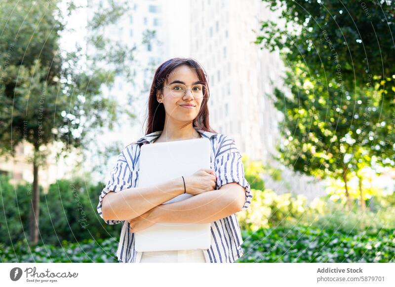 Junge Frau hält einen Laptop im Freien im Frühling urban Park Großstadt Grün Gebäude heiter Lächeln jung Technik & Technologie professionell Schüler Bildung