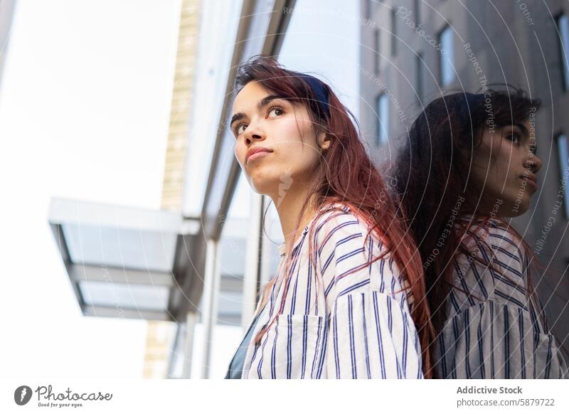 Junge Frau, die in einer städtischen Umgebung nach oben blickt jung urban reflektierend nachdenklich Starrer Blick Gebäude Glas Großstadt Porträt Frühling