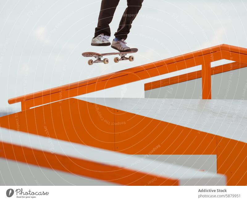 Skater, der einen Trick auf dem Orange Skate Park Rail ausführt Skateboarderin Schlittschuh springen Skateboarding Schiene Hintergrund Grinden manuell Person
