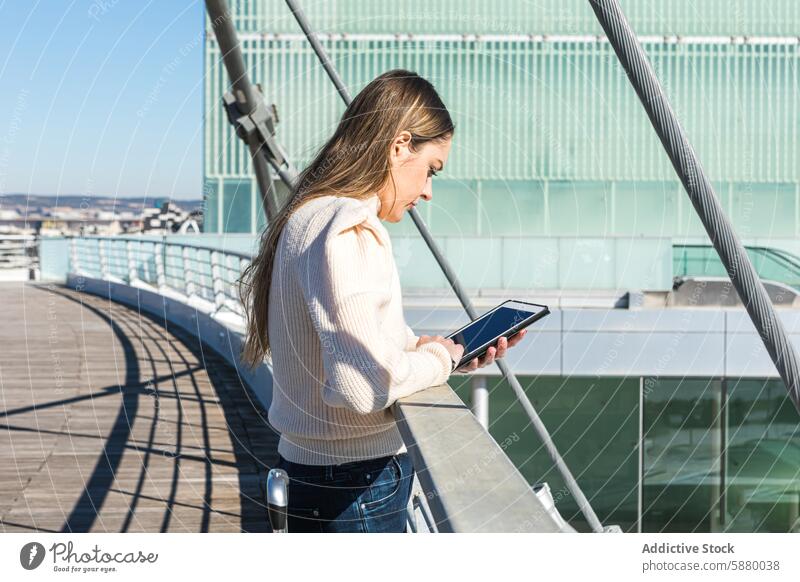 Frau mit Tablet auf einer sonnigen Brücke Stadtbild Technik & Technologie Tablette Himmel modern Steg Gerät Apparatur im Freien herabsehend Sonnenlicht Tag