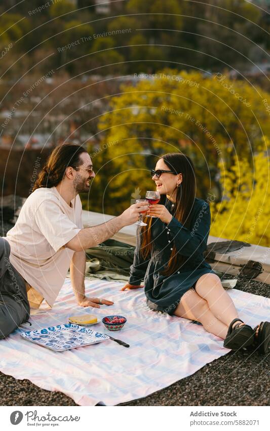 Pärchen genießt ein Picknick bei Sonnenuntergang auf der Dachterrasse Paar Wein Zuprosten romantisch Mann Frau Grün Stadtansicht Sonnenschein im Freien Freizeit