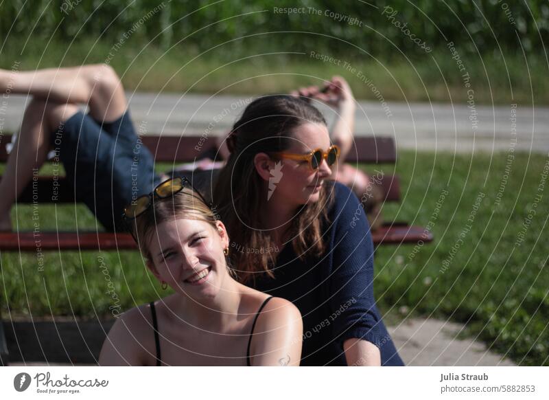 Pause Gruppe Frauen Sonnenbrille Sommer Bank liegen ausruhen lachen Pause machen sitzen draußen Sitzbank Park zusammen Handy halten Mann kurze hose grüne Wiese