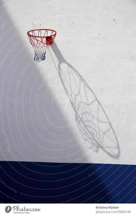 basketballkorb mit schattenwurf netz wand mauer hängen licht sonne sonnig draußen ballsport hobby freizeit spiel spielen