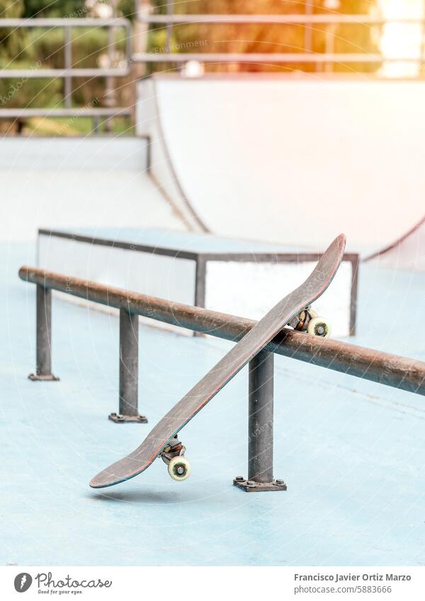 Skateboard, das gegen eine Schiene in einem Skatepark gelehnt ist. Rampe leer im Freien Sport Erholung Schlittschuhlaufen sonnig Schiffsdeck Wagenräder Grinden