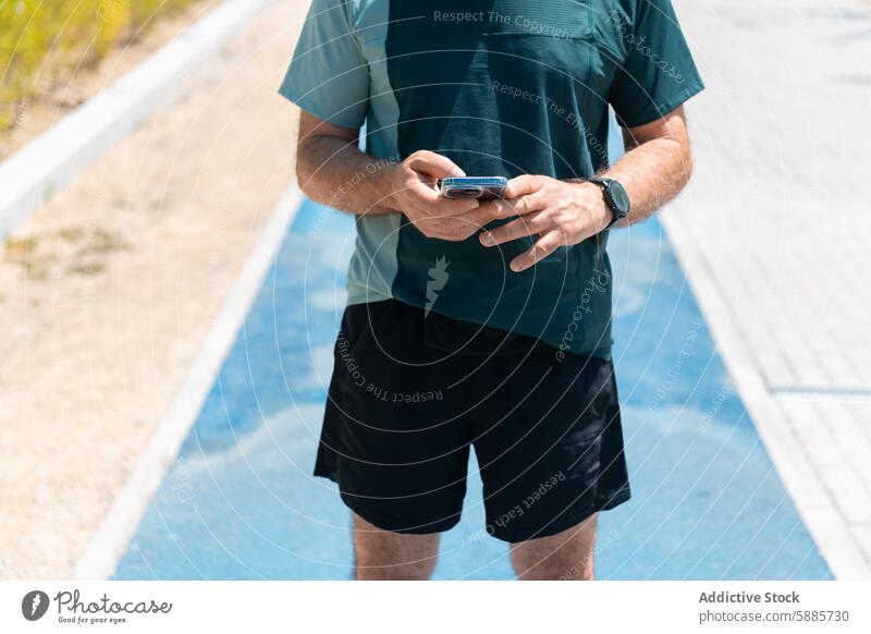 Unbekannter Mann prüft Smartphone auf der Laufbahn Fitness Sportbekleidung Technik & Technologie mittleren Alters Übung im Freien tagsüber Sommer Telefon Athlet