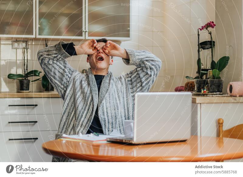 Gestresster Mann im Home Office mit Händen über den Augen Stress heimwärts Büro Tisch Laptop Robe Verzweiflung frustriert Küche im Innenbereich Orchidee Pflanze