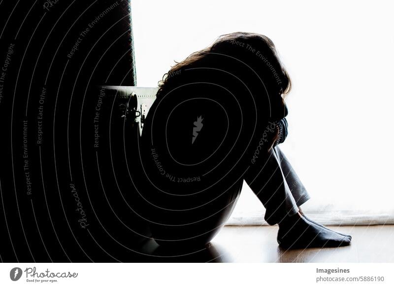 Unglücklichsein. Frau in Silhouette, auf dem Boden sitzend mit Gegenlicht. Deprimierende Gedanken. Schattenspiel abstrakt Missbrauch Erwachsener allein Angst