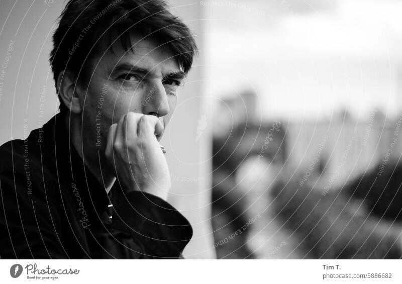 Mann mit Blick in die Kamera raucht eine Zigarette Rauchen Balkon Berlin Außenaufnahme Mensch Hand Gesicht Schwarzweißfoto Porträt Erwachsene