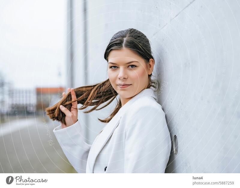 lächelnde junge Frau lehnt an einer Wand frau entspannt junge frau nachdenklich sinnlich verträumt porträt glücklich single optimistisch fröhlich zuversichtlich