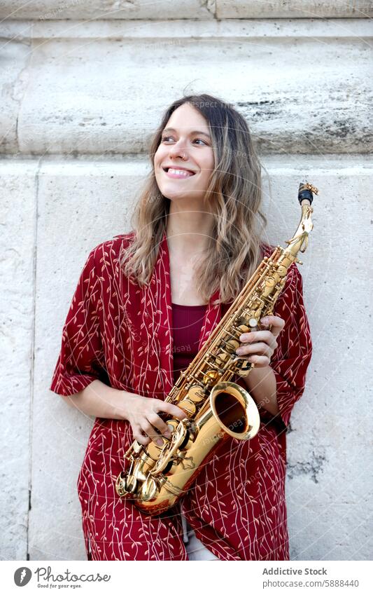 Frau spielt fröhlich Saxophon in stilvollem Outfit Musik freudig Kaukasier Spielen rot Overall Lächeln Stil Musiker urban Hintergrund Leistung Instrument Glück