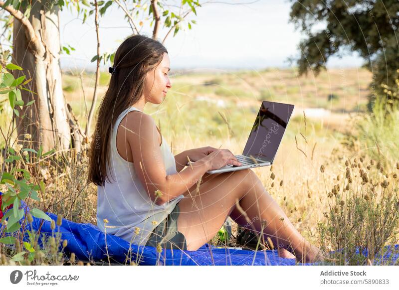 Junge Frau arbeitet an einem Laptop in einer ländlichen Umgebung im Freien Natur Arbeit Gras Baum Feld Technik & Technologie abgelegen Umwelt Landschaft Sommer