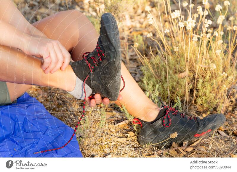 Wanderer passt seine Schuhe auf einem Feldweg an Anpassung Trekking Schlafsack Natur Landschaft Nachlauf im Freien Abenteuer Freizeit Aktivität Fitness