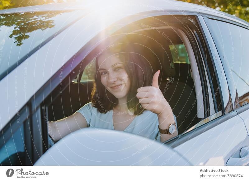 Junge Frau gibt vom Auto aus Daumen hoch PKW Fahrer Lächeln gestikulieren Sitz Befriedigung Sicherheit sonnig Tag jung Fahrzeug Verkehr fahren positiv Glück