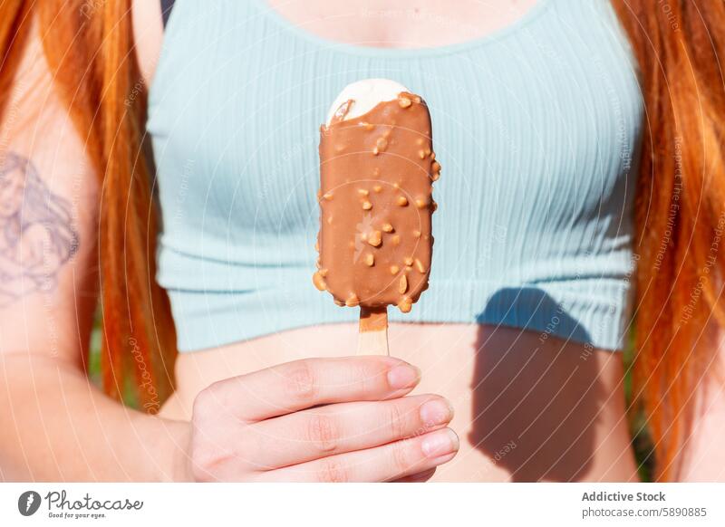 Sommerlicher Genuss mit einer Schokoladeneistafel Frau Speiseeis Leckerbissen sonnig Tag Ablass Dessert Hand Halt Snack im Freien Freizeit Saison süß