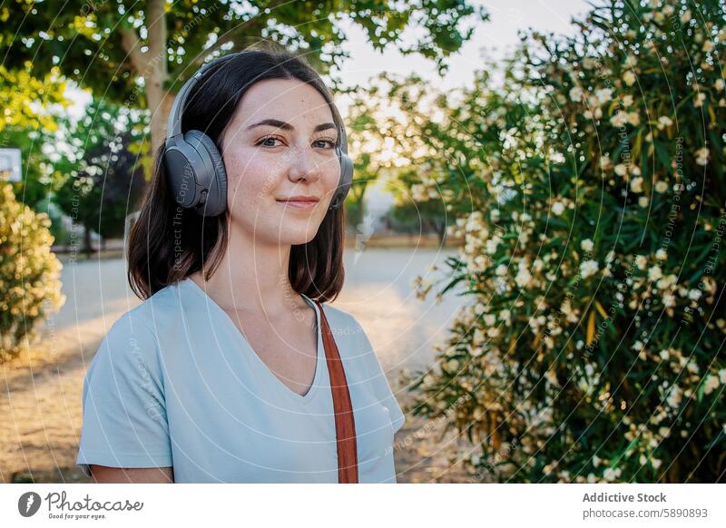 Junge Frau genießt Musik mit Kopfhörern in einem Park Grün Blumen friedlich jung Erwachsener Freizeit Genuss hören Sommersprossen Apparatur Gerät Natur