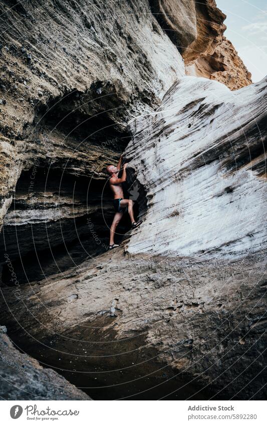 Junger Mann klettert an einem sonnigen Tag auf einen Felsen in der Nähe einer Höhle Abenteuer Sommer Feiertag Klettern Natur im Freien Erkundung reisen