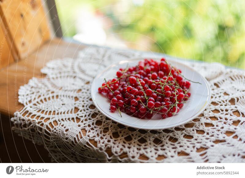 Frische Johannisbeeren auf einer Spitzentischdecke bei natürlichem Licht Beeren Teller Tischwäsche frisch Sommer pulsierend Farbe rot Frucht Gesundheit