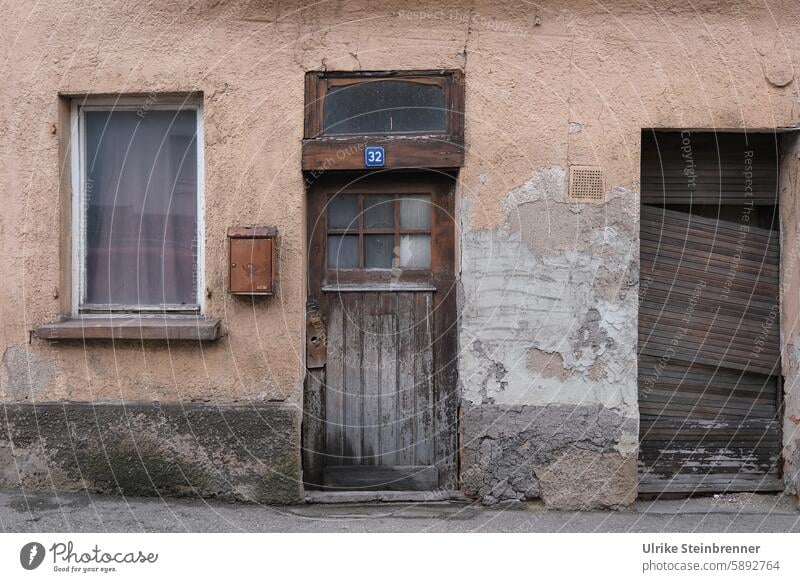 Fenster und Türen eines unbewohnten Altbaus Eingang Haus Gebäude Fassade Briefkasten Eingangstür Holztür Haustür alt sanierungsbedürftig zerfallen Immobilie