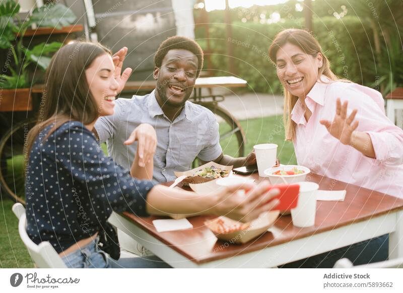 Multiethnische Freunde führen während des Mittagessens einen Videoanruf Lächeln Wellenhand Gruß Zusammensein Straße Restaurant Tisch Glück online heiter