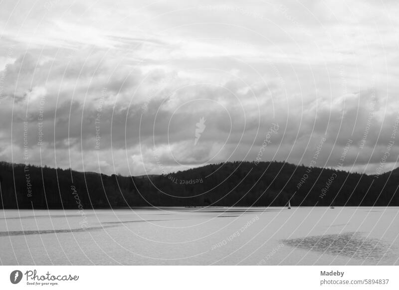 Heraufziehendes Unwetter mit bedrohlichen Wolken über den Bergen des Kellerwald mit Segelbotten auf dem Edersee im Kreis Waldeck-Frankenberg in Hessen in neorealistischem Schwarzweiß