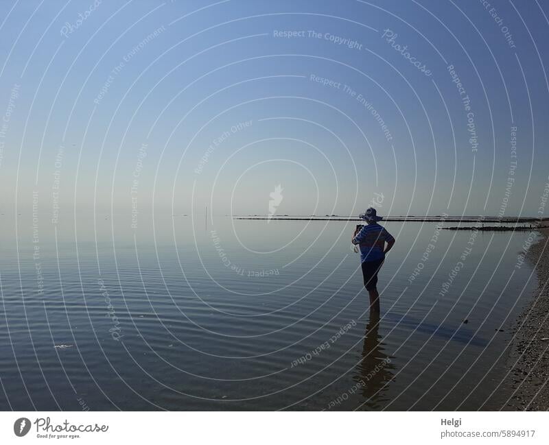 Hallig Gröde | Silhouette einer Frau mit Sonnenhut und Smartphone im Wattenmeer Mensch Seniorin Sonnenlicht Licht Schatten Meer Nordsee Wasser Himmel Natur