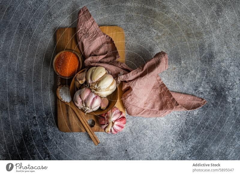 Rustikaler Knoblauch und Gewürze auf einem Schneidebrett in der Küche hölzern rustikal Leinen Stoff warm texturiert Zusammensetzung Hintergrund grau ganz Knolle