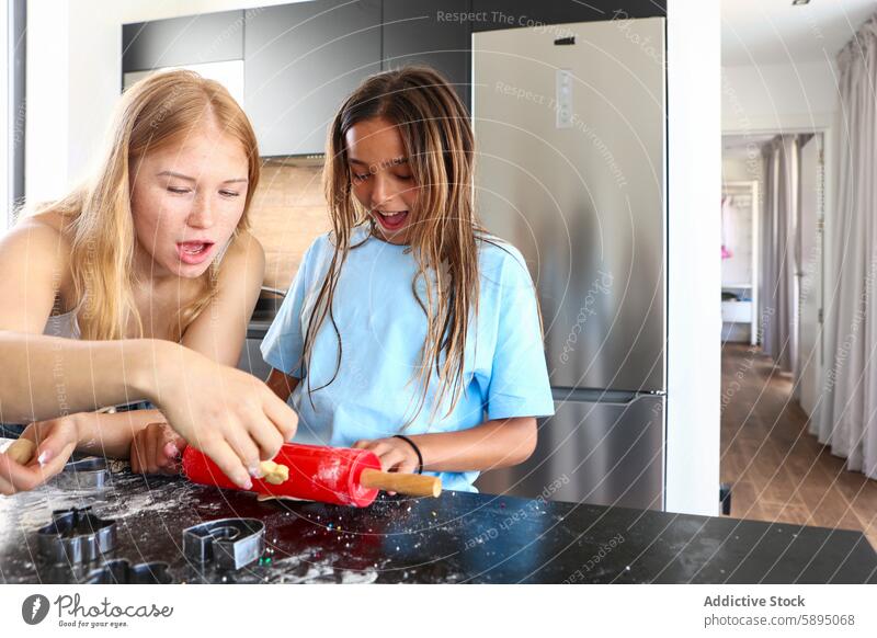 Zwei Schwestern beim Plätzchenbacken in einer Wohnküche Triplett Küche Essen zubereiten Keks Nudelholz Teigwaren spielerisch heimwärts Geschwisterkind Familie