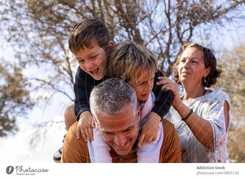 Die Familie genießt die gemeinsame Zeit im Freien im Herbst Park Vater Mutter Söhne Jungen Geschwister Freude lachen Natur Interaktion Bruder Lächeln