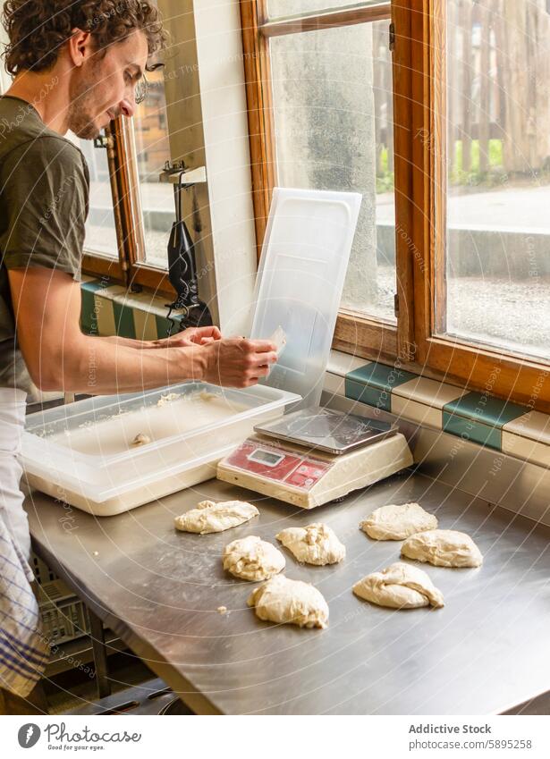 Bäcker bei der Teigzubereitung in einer Küche mit Blick auf den Garten Pizza Teigwaren Skala Fenster Sonnenlicht rustikal Qualität penibel Portion digital