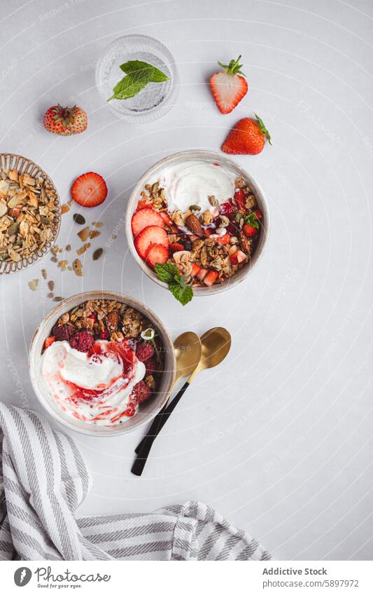 Ansicht von oben: Gesundes Sommerfrühstück mit Joghurt und Müsli Frühstück Erdbeeren Himbeeren Mandel Minze nahrhaft Gesundheit heller Hintergrund